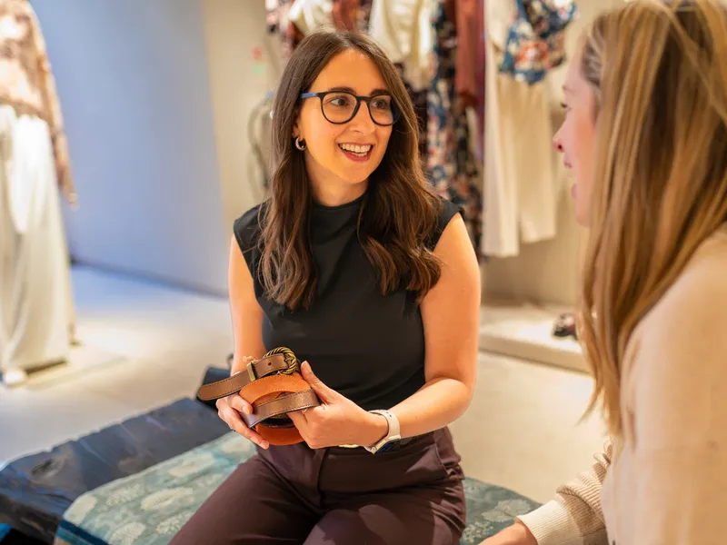 Maria Pastor showing a client a choice of belts in a clothes shop