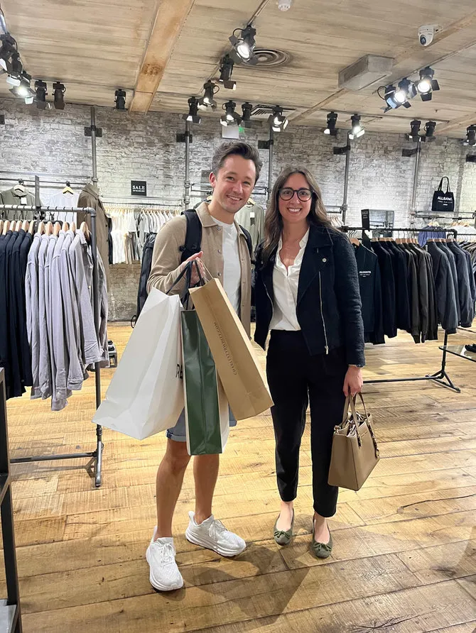 Maria Pastor with a smiling client carrying his shopping bags in a menswear store