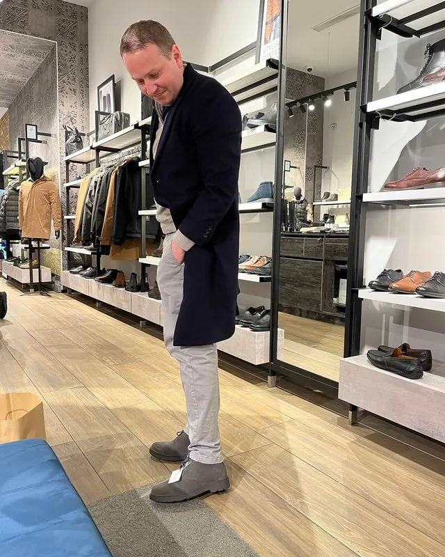 A client trying on grey suede boots in a menswear shop during men's personal shopping