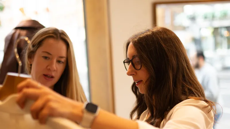 Maria Pastor holding up a cream shirt for a client to consider in a shop
