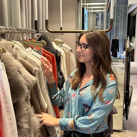 Maria Pastor choosing garments from a rail during a personal shopping session