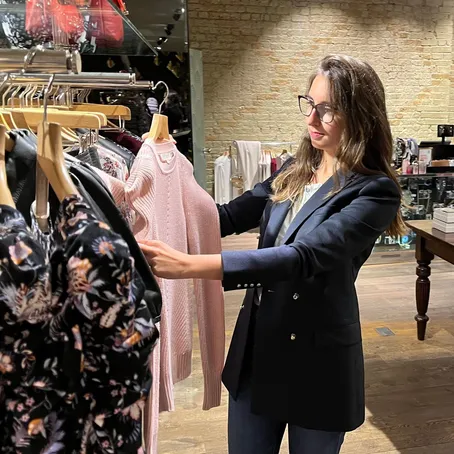 Maria Pastor holding up a garment for a client to consider