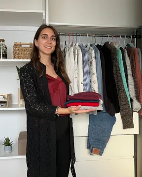 Maria Pastor holding curated clothing selections during a wardrobe edit session