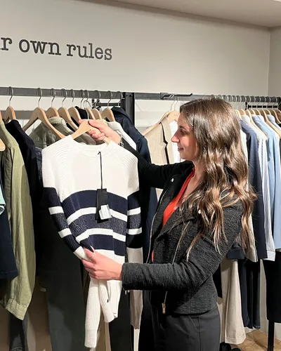 Maria Pastor holding up a striped jumper from a rail of clothes