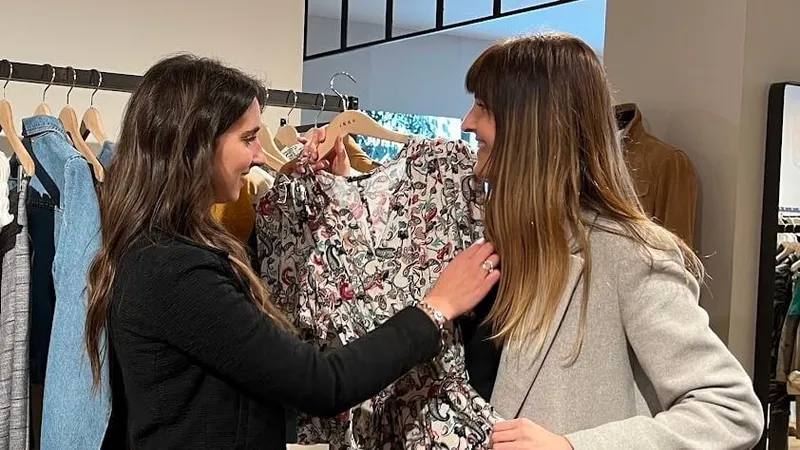 Maria Pastor holding a floral dress up to a client in a boutique