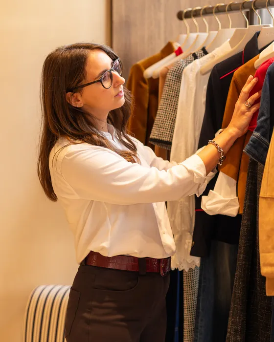 Maria Pastor, personal shopper in Oxford, choosing pieces from a rail of clothes before a client arrives