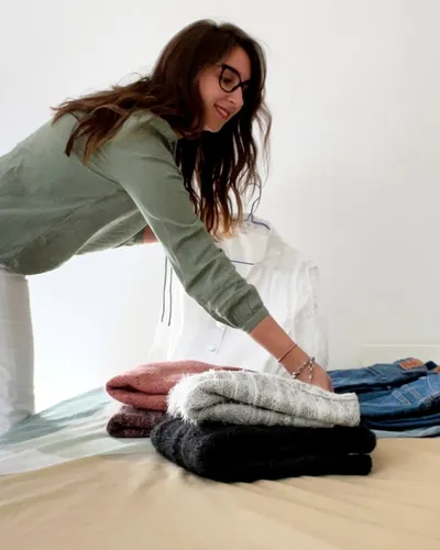 Maria Pastor sorting folded jumpers and jeans on a bed