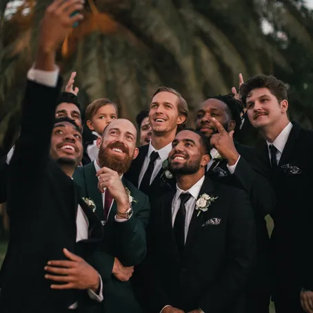 Groomsmen in suits standing together outdoors