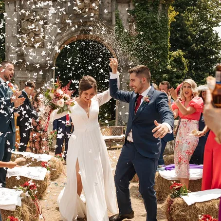 A bride and groom walking through a shower of confetti after their ceremony