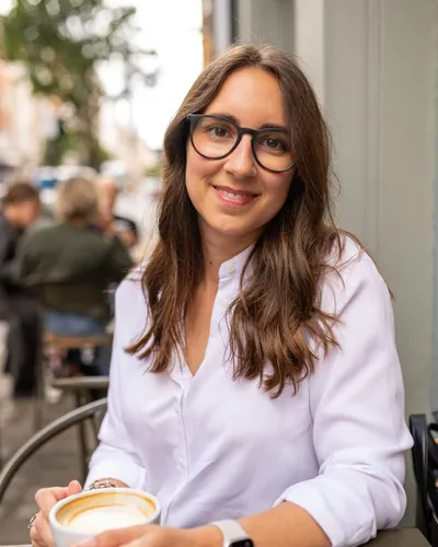 Maria Pastor smiling at a café table with a cup of coffee